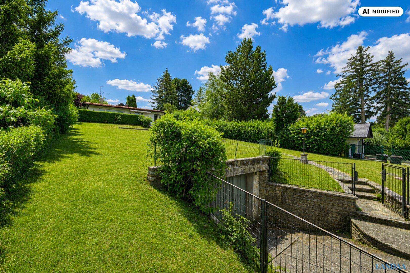 Gepflegter Garten mit Hanglage und einem Zugang zu einer möglichen Tiefgarage oder Kellerbereich.