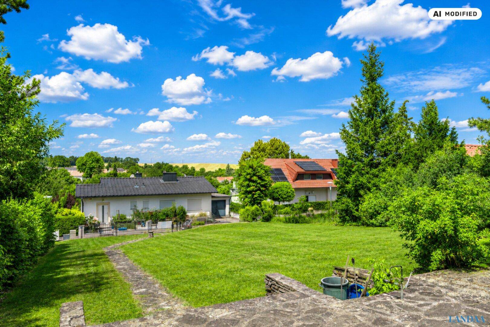 Weitläufiger Gartenbereich mit Rasenfläche und Blick auf benachbarte Häuser und die ländliche Umgebung.
