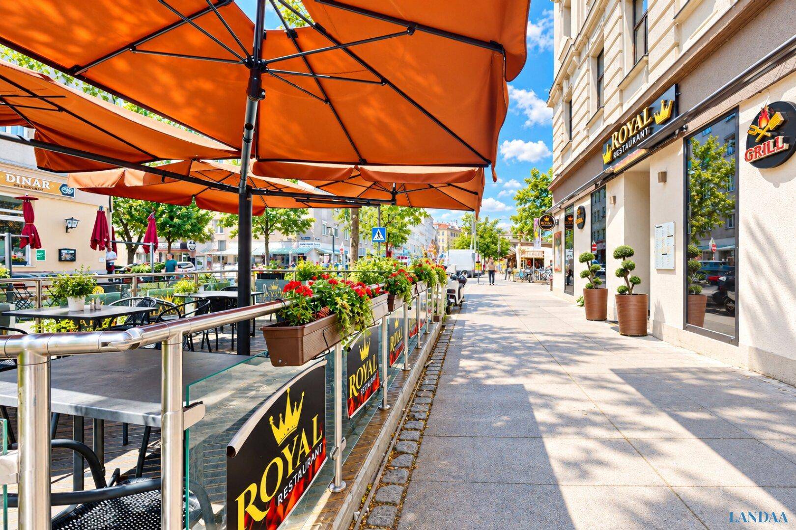 Lebhafter Außenbereich des Restaurants mit großen Sonnenschirmen und Tischen entlang des Gehwegs.