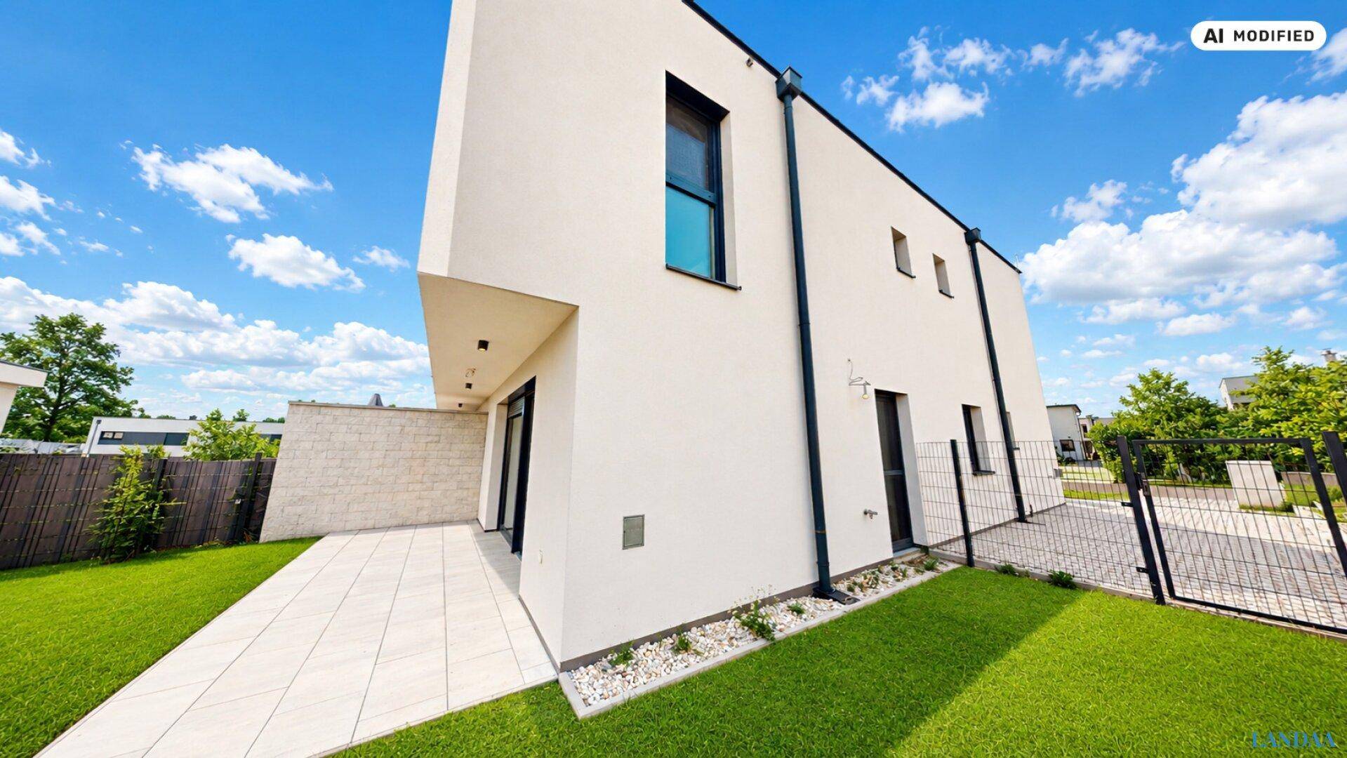 Moderne Hausfassade mit gepflegtem Garten, Gehwegen und klarem Himmel.