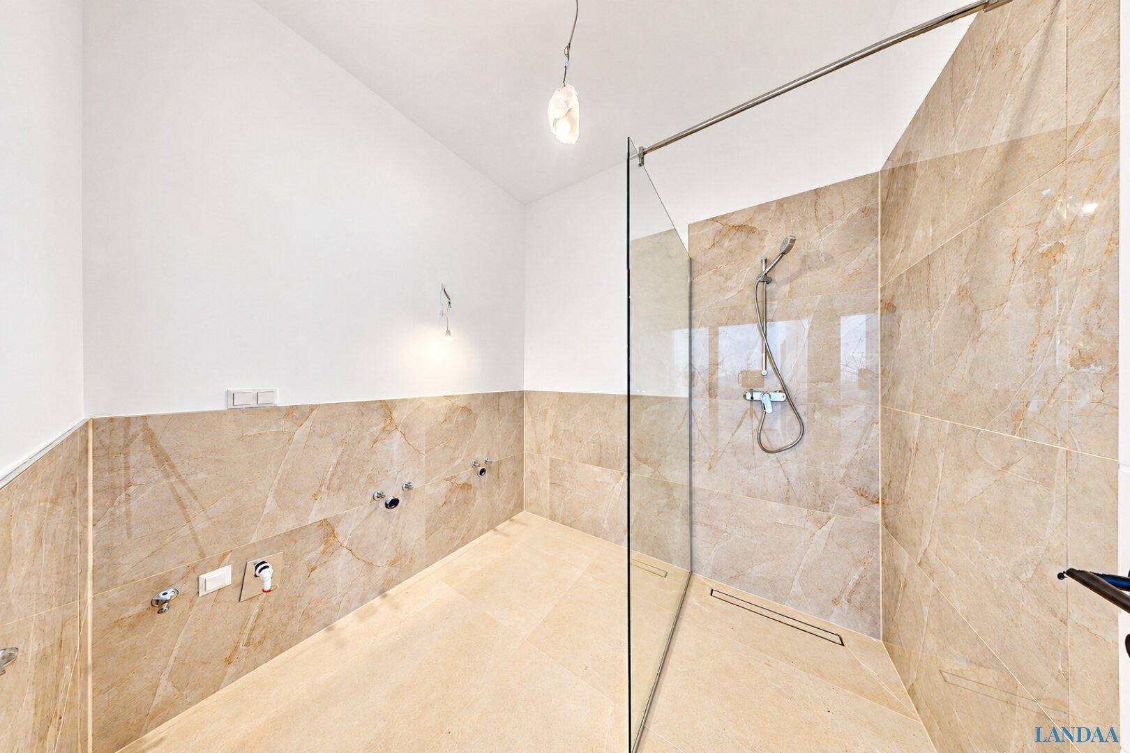 Modernes Badezimmer mit begehbarer Dusche und großformatigen Fliesen in Marmoroptik.