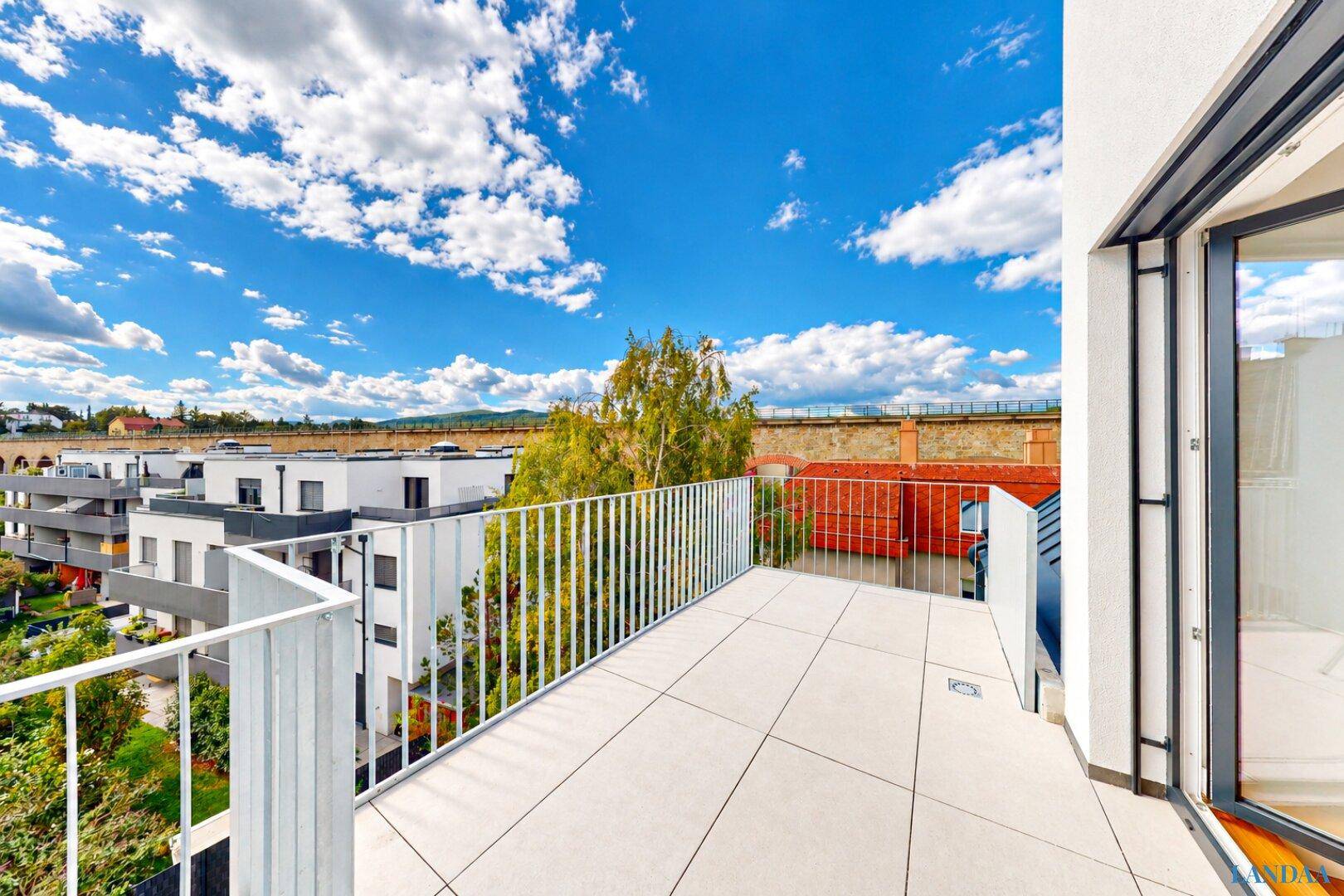 Geräumiger Balkon mit Fliesenboden und Metallgeländer, bietet einen weiten Ausblick.