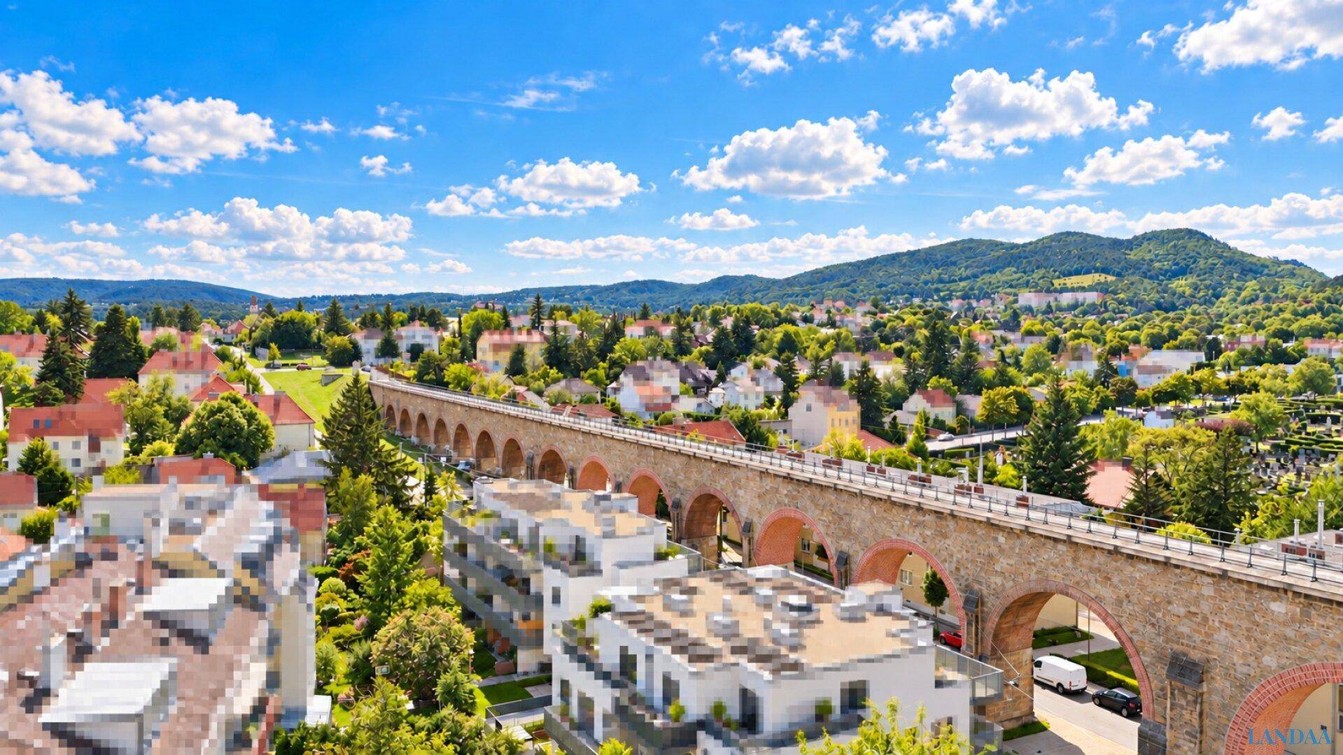Weitläufiger Blick über eine Wohngegend mit viel Grün und einem historischen Viadukt.