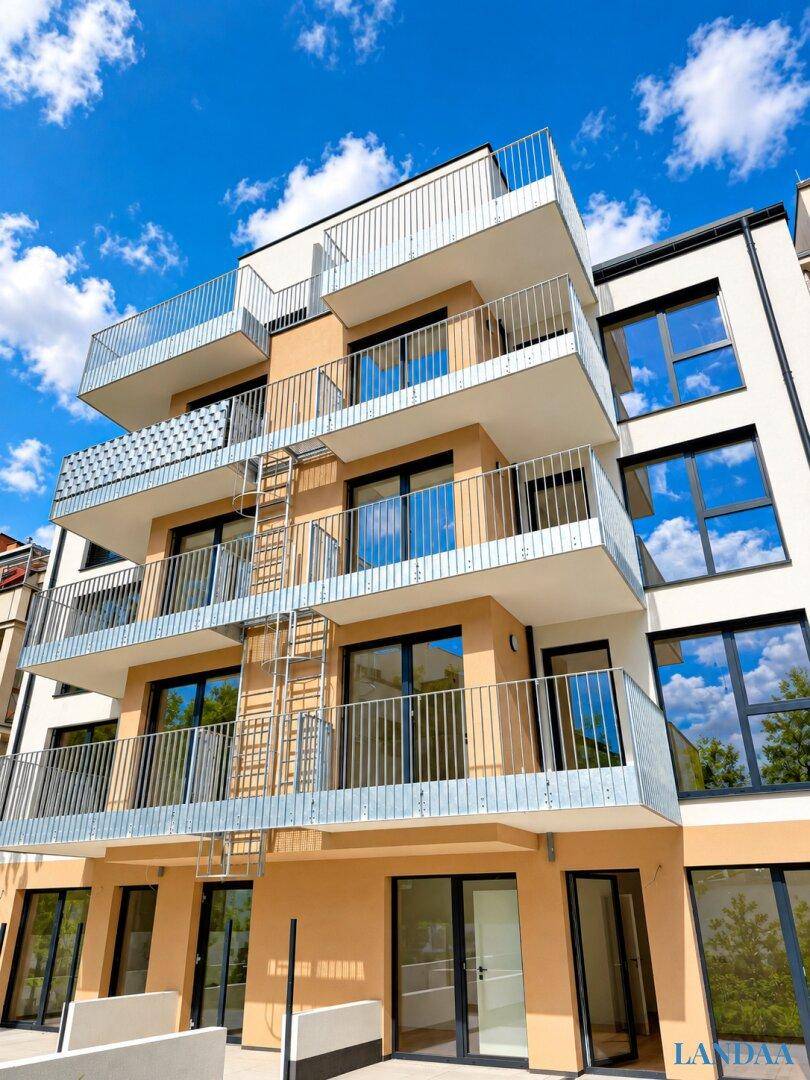 Vorderansicht eines modernen Mehrfamilienhauses mit Balkonen und großen Glasflächen.