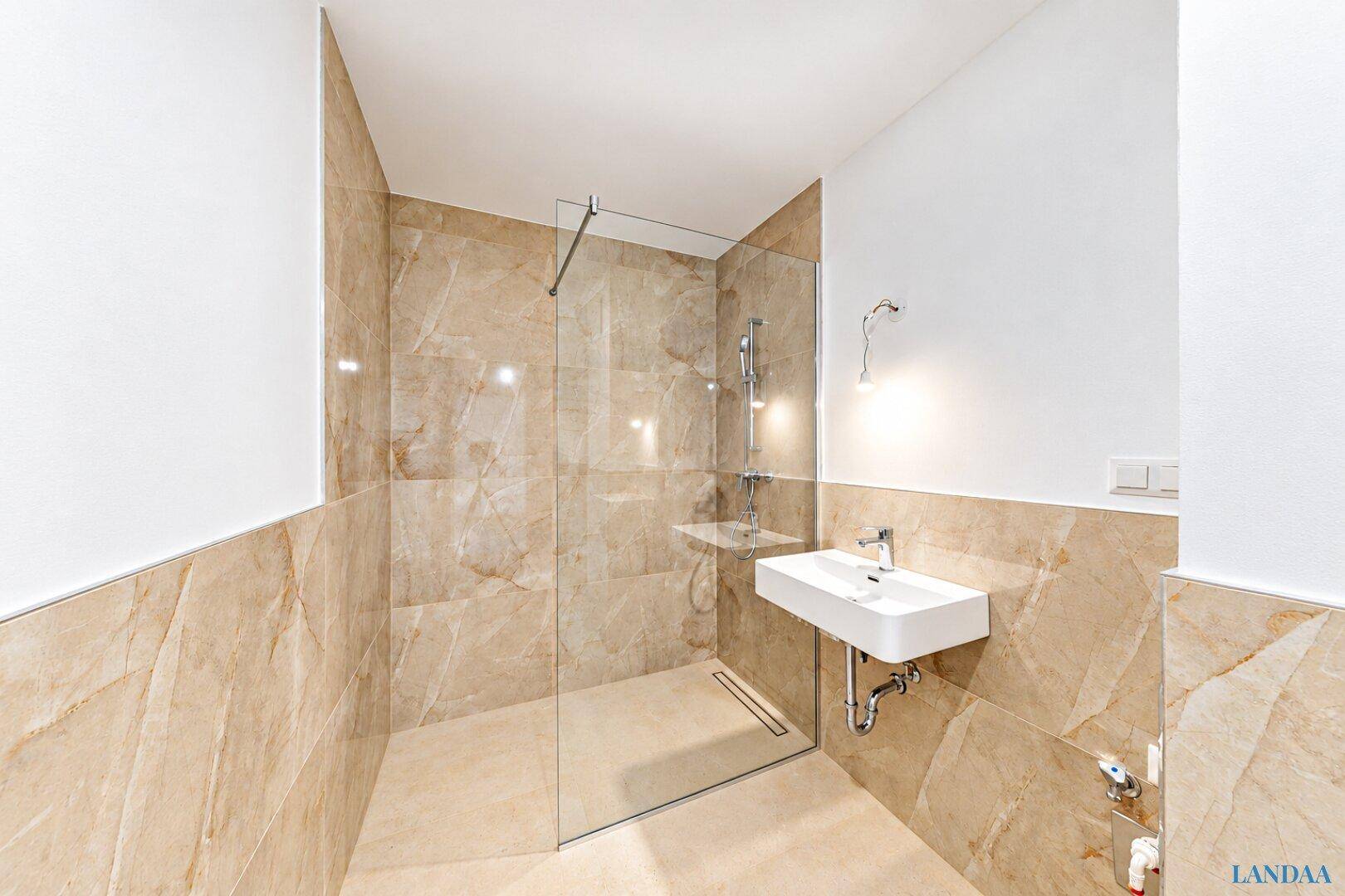 Elegantes Badezimmer mit begehbarer Dusche, modernem Waschbecken und Marmorfliesen.