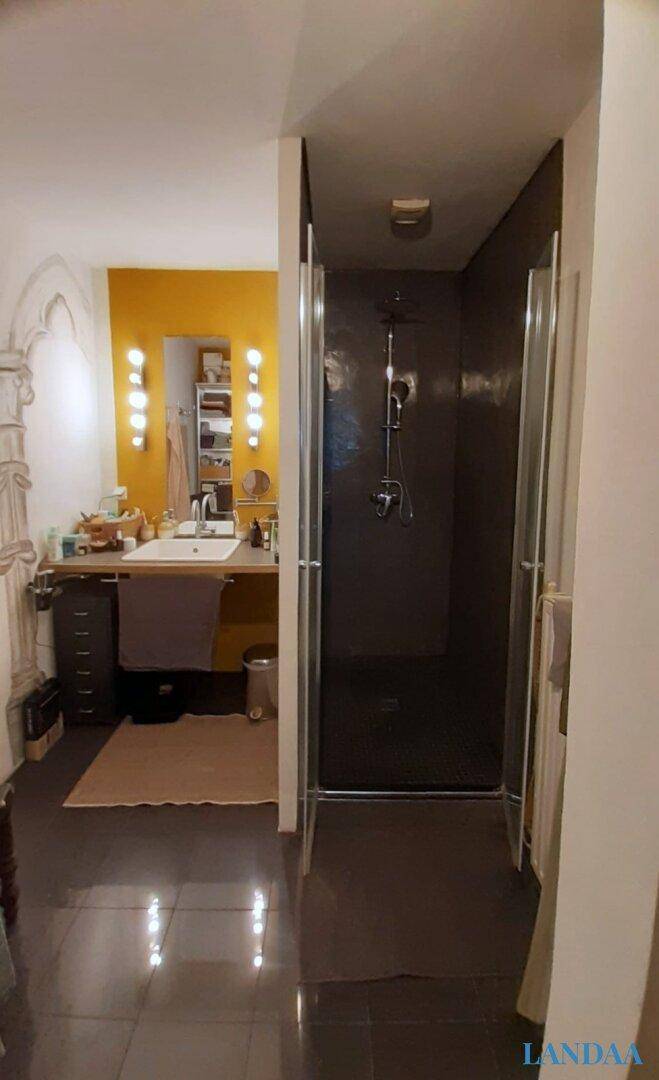 Modernes Badezimmer mit gelber Akzentwand, Einzelwaschbecken und einer geräumigen begehbaren Dusche.