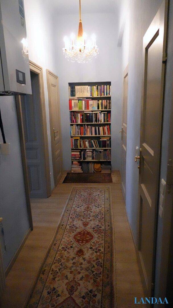 Langer Flur mit Holzboden, Bücherregal und einem Kronleuchter an der Decke.