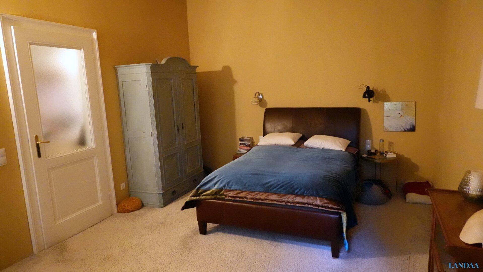 Gemütliches Schlafzimmer mit gelben Wänden, einem Doppelbett und einem hellblauen Kleiderschrank.