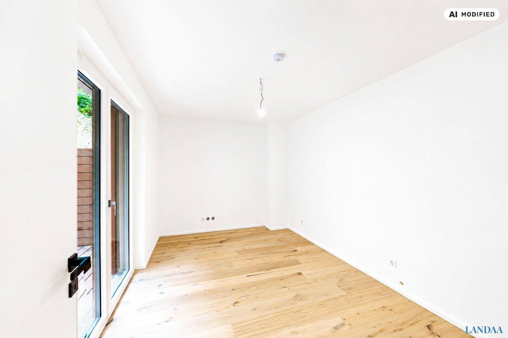 Heller, leerer Raum mit Holzboden und Glastür zum Außenbereich.