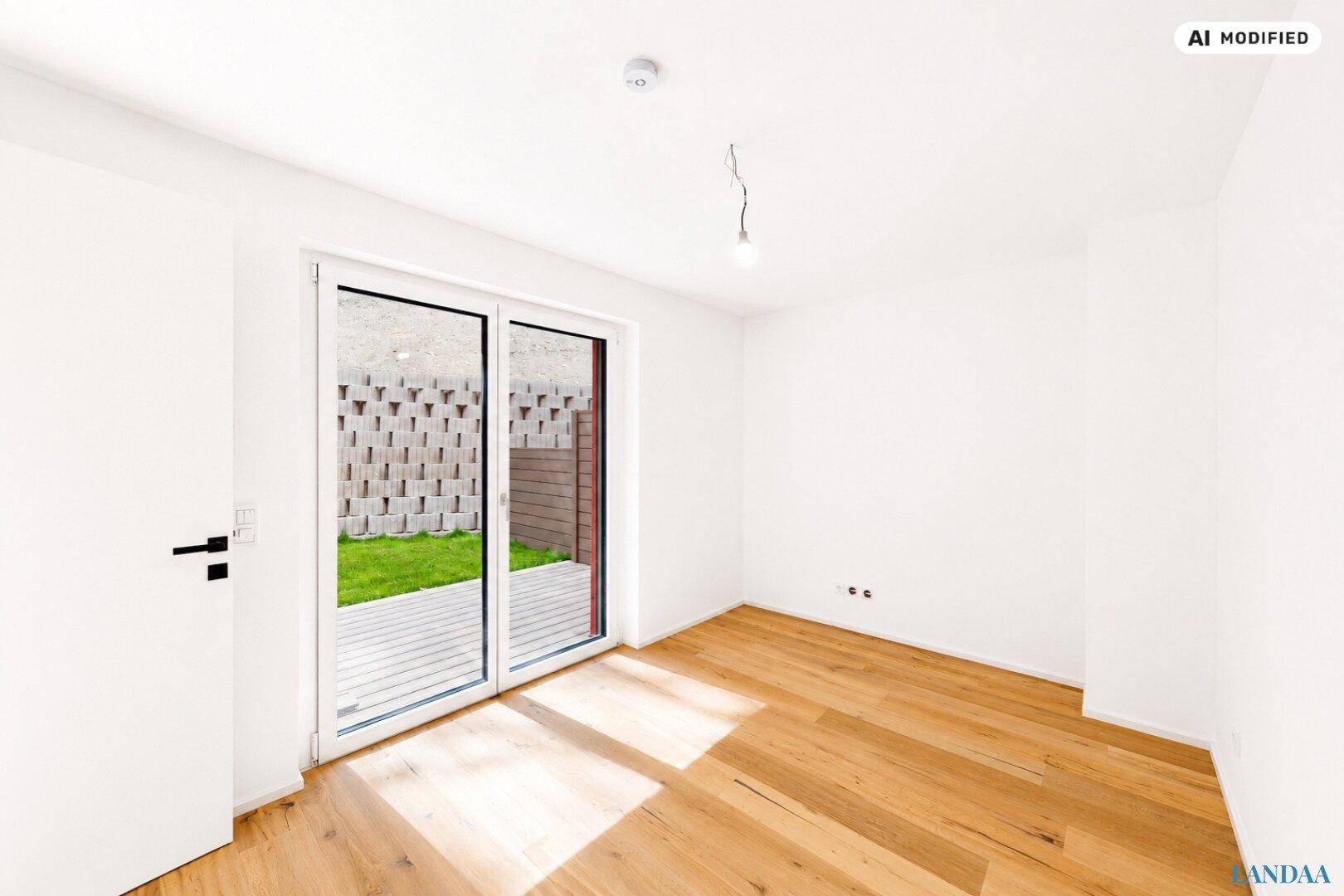Heller, leerer Raum mit Holzboden und Glasschiebetür zur Terrasse und Garten.