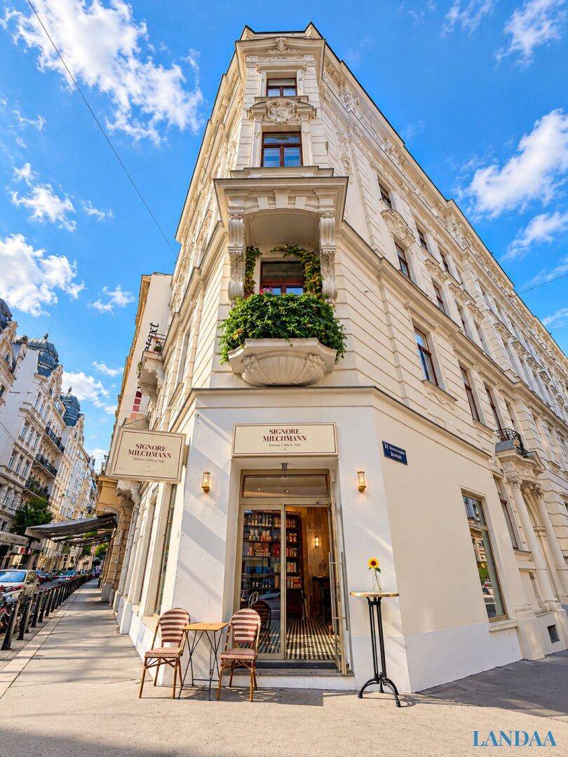Elegantes Eckgebäude mit klassischer Architektur und einem kleinen Balkon mit Pflanzen.