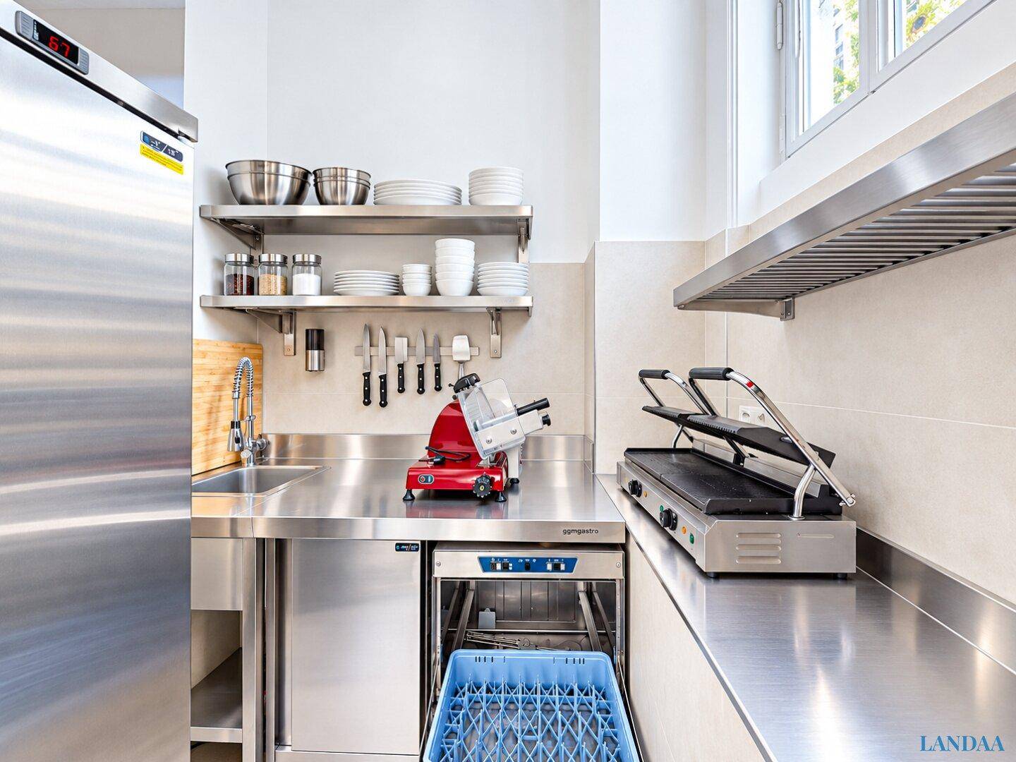 Funktionale Gewerbeküche mit Edelstahlarbeitsflächen, Spülmaschine und professionellen Geräten.