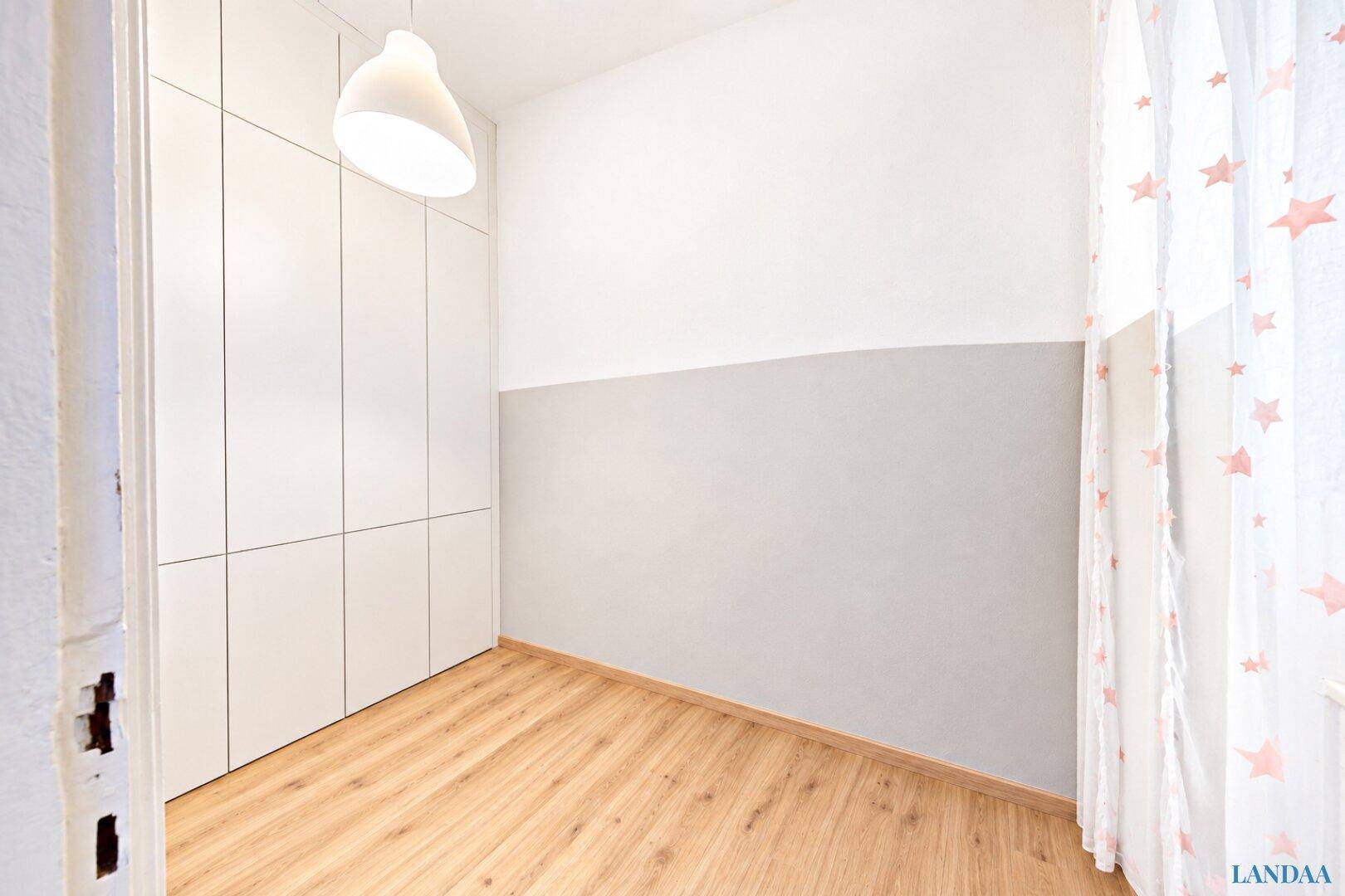 Leeres Zimmer mit hellen Einbauschränken und modernem Laminatboden, bereit zur individuellen Gestaltung.