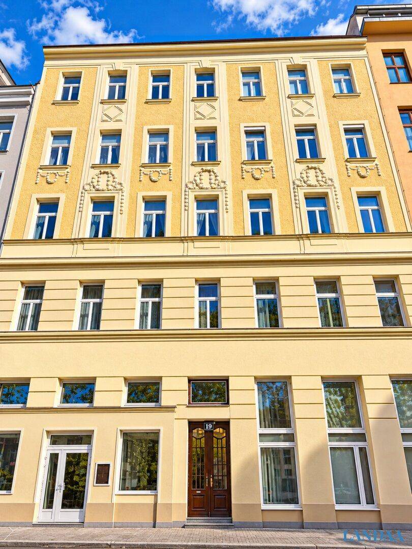 Klassische Fassade eines gelben Mehrfamilienhauses mit vielen Fenstern und dekorativen Elementen.
