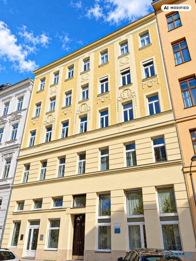 Historisches Gebäude mit gelber Fassade und vielen Fenstern unter blauem Himmel.