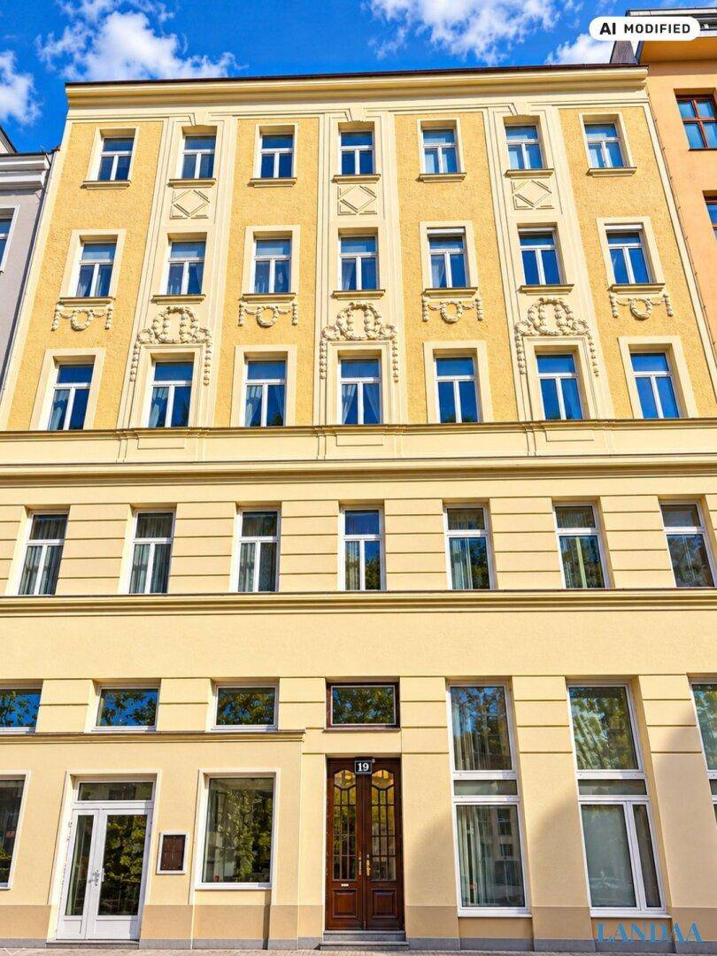 Gelbe Fassade eines Mehrfamilienhauses mit klassischer Architektur und vielen Fenstern.