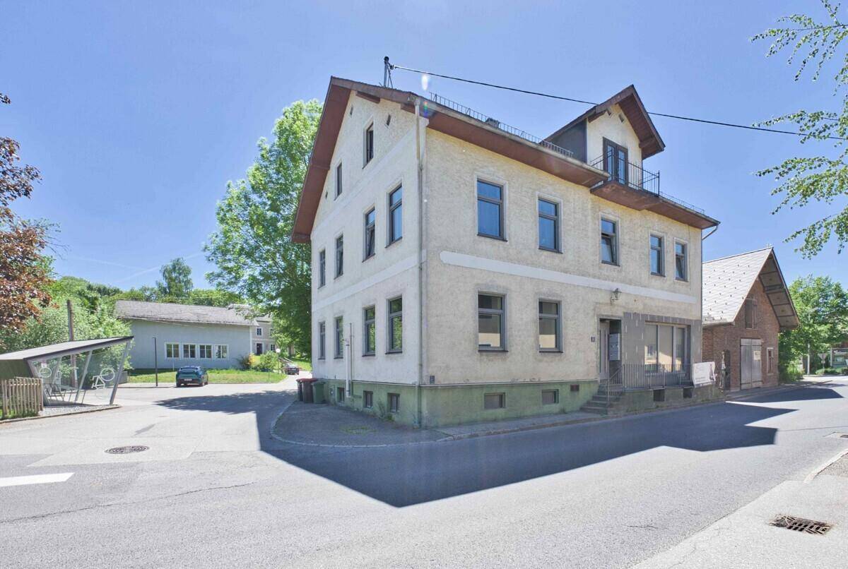 Gebäudeansicht von der Straßenseite mit Eingangsbereich und einem kleinen Balkon im Obergeschoss.