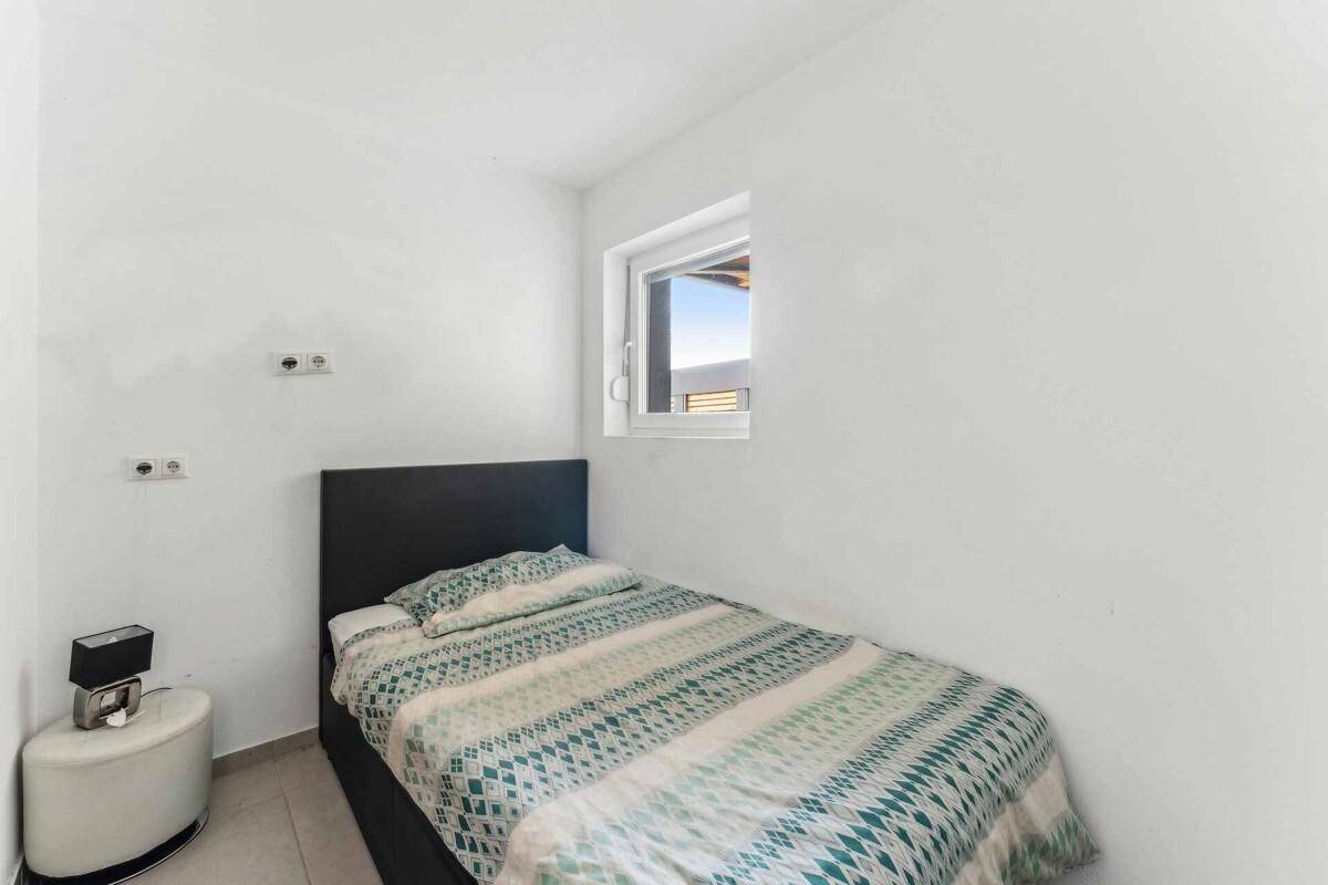Kleines Schlafzimmer mit Einzelbett, weiß gestrichenen Wänden und Fenster.