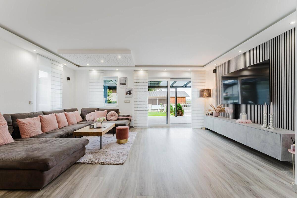 Helles Wohnzimmer mit großem Ecksofa, modernem TV-Bereich und Zugang zur Terrasse.