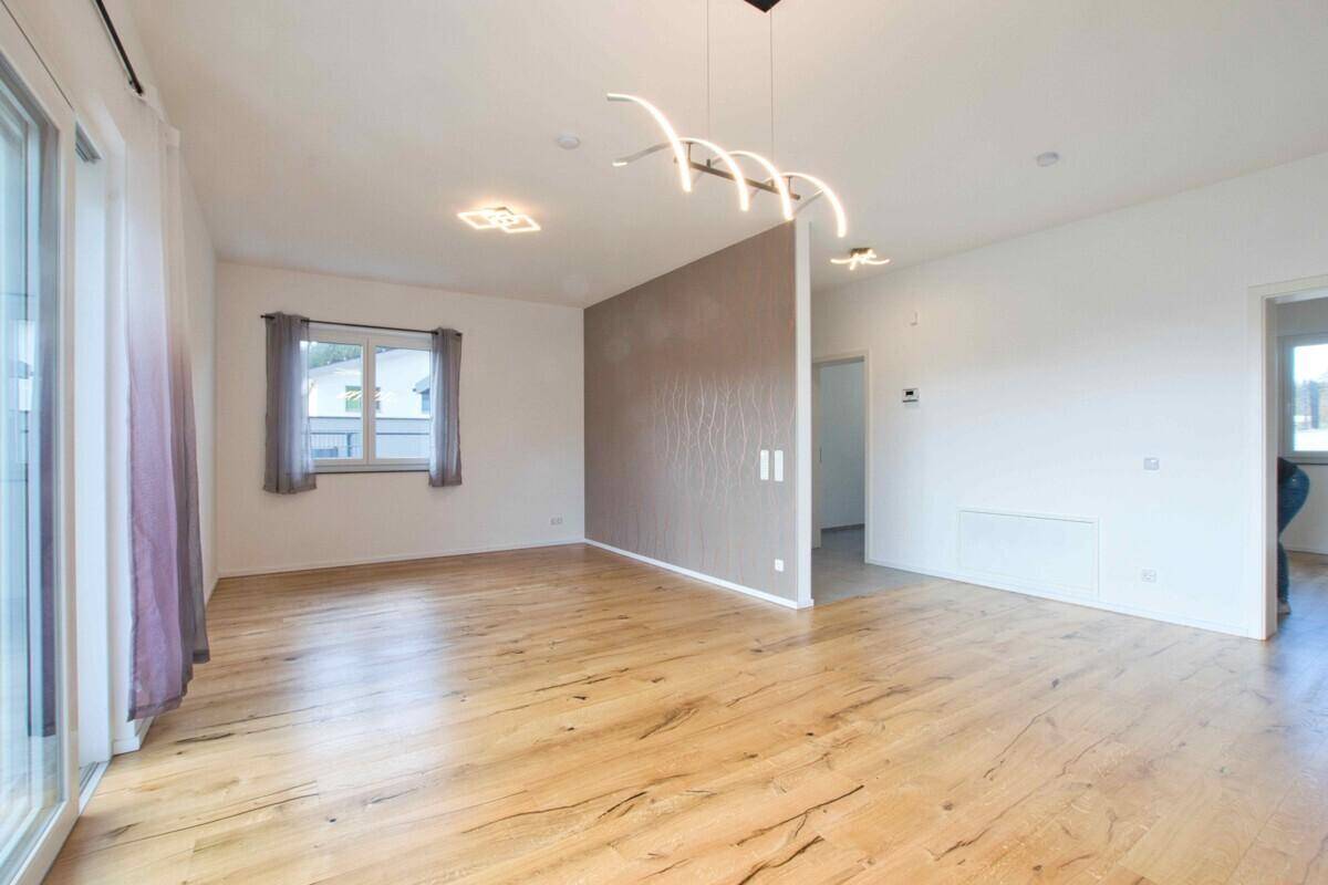 Helles Wohnzimmer mit modernem Holzboden und einer Trennwand.