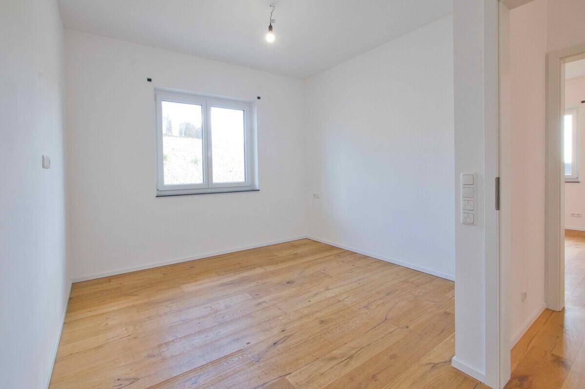 Freundliches Zimmer mit Holzboden und Fenster, ideal als Schlaf- oder Arbeitszimmer.