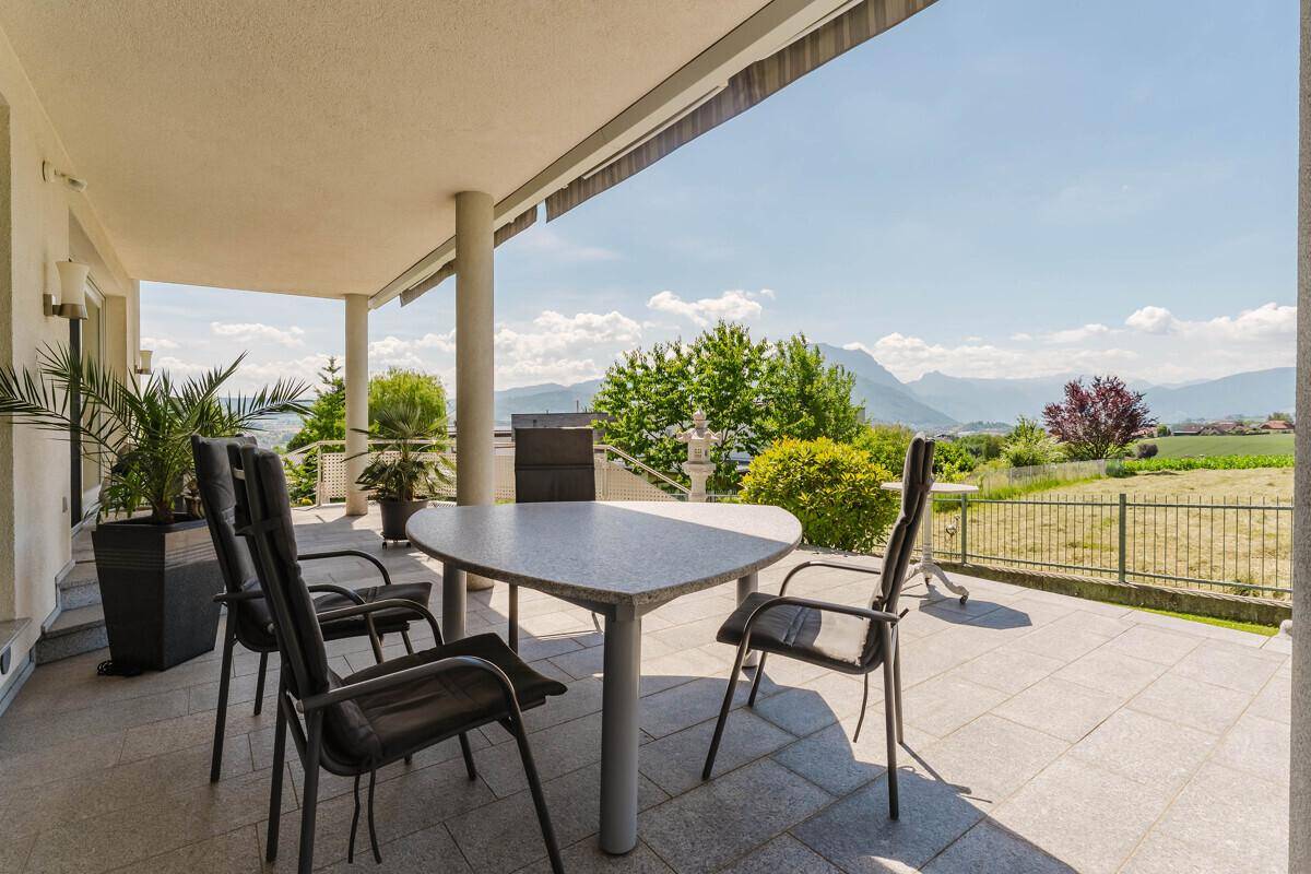 Überdachte Terrasse mit Sitzgelegenheiten, ideal für Mahlzeiten im Freien und Bergblick.