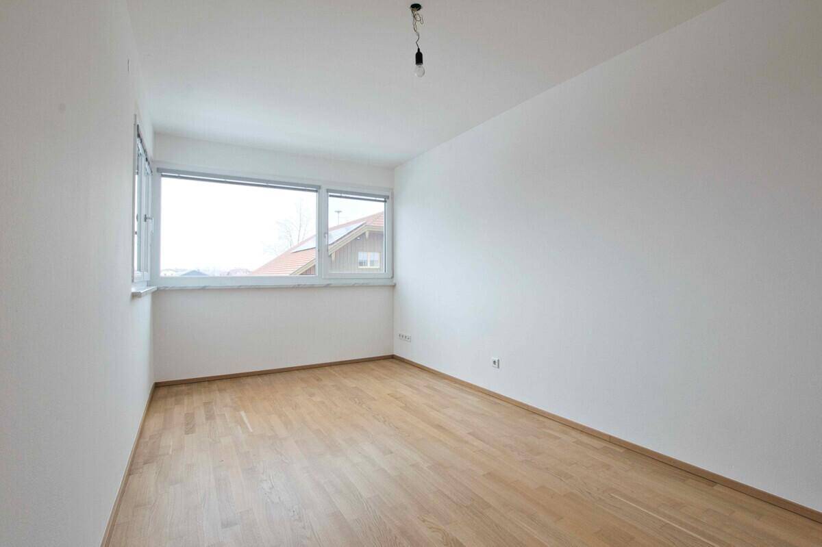 Geräumiger, leerer Raum mit Parkettboden und weitem Blick aus dem Fenster.