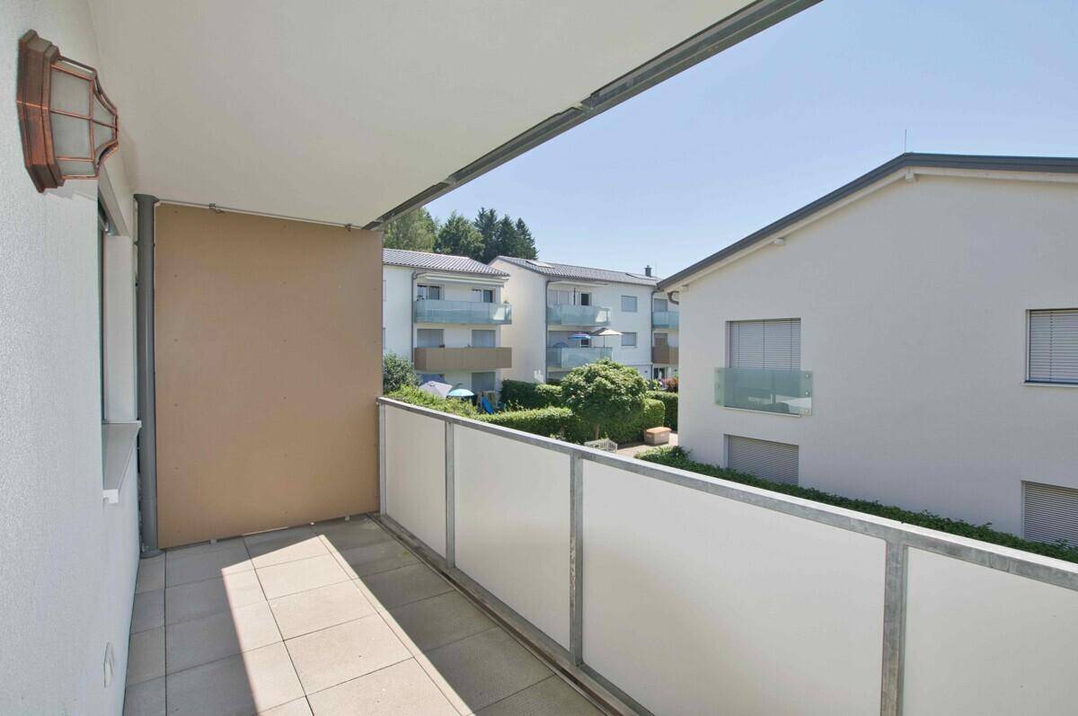 Heller Balkon mit Fliesenboden und Blick auf die umliegenden Gebäude und Grünflächen.