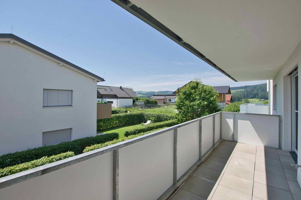 Geräumiger Balkon mit Fliesenboden und weitem Blick über die grüne Landschaft.
