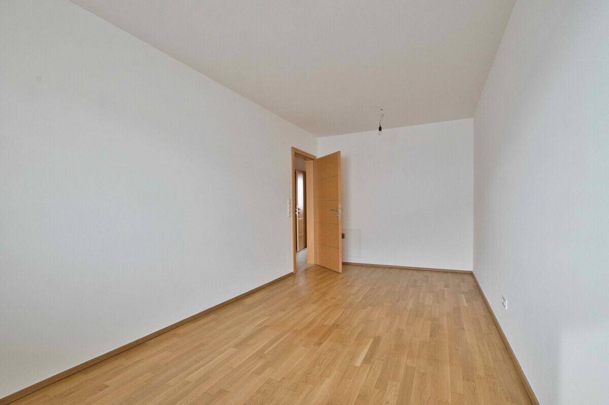 Heller, unmöblierter Raum mit Holzboden und einer Holztür.
