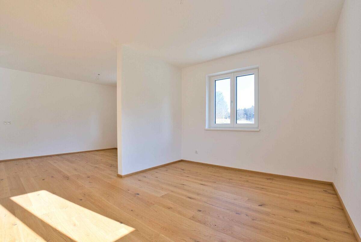 Lichtdurchfluteter Raum mit Holzboden und weiß gestrichenen Wänden, ideal für Wohnzwecke.