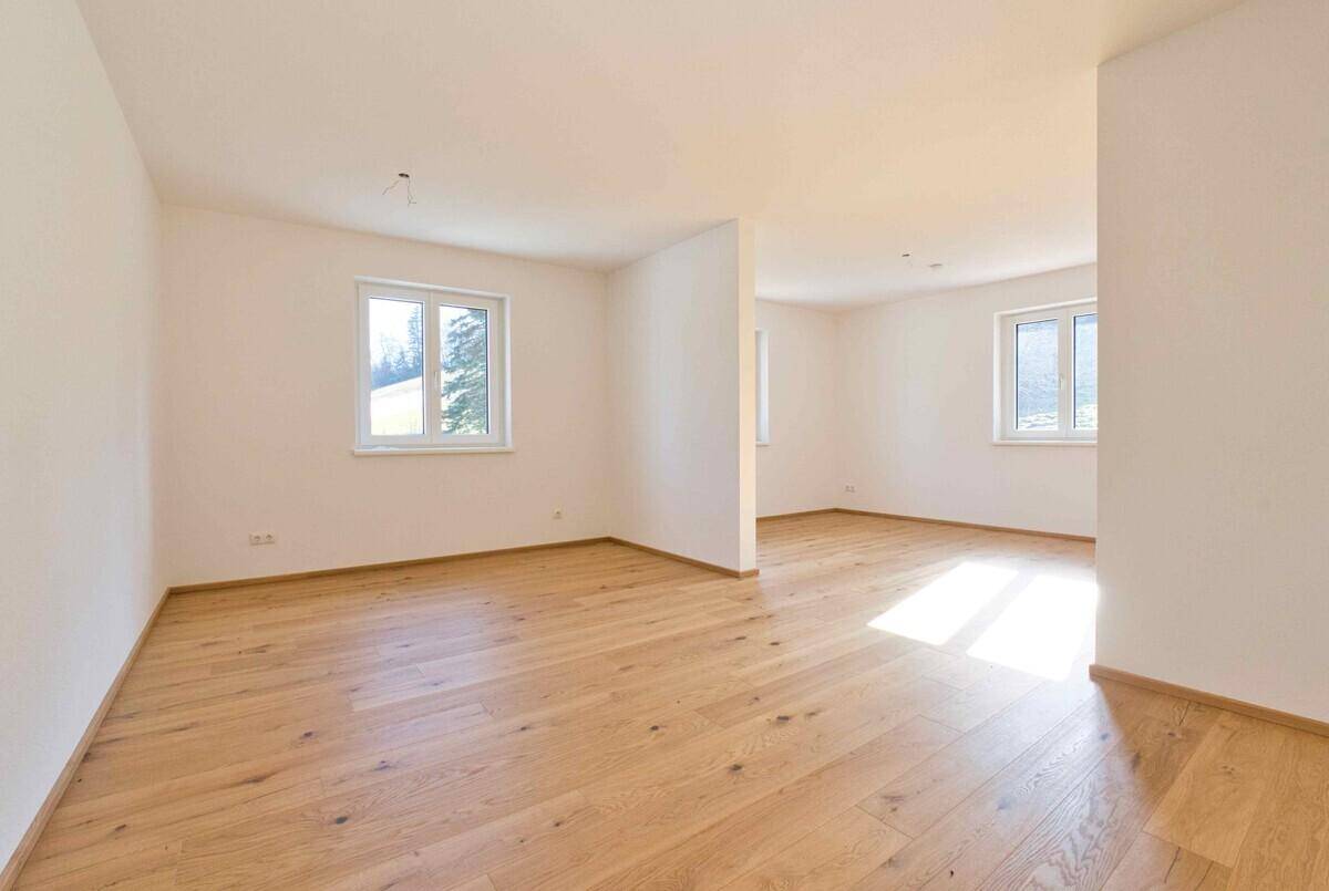 Heller, leerer Wohnbereich mit Eichenparkett und großen Fenstern, bereit zur Einrichtung.