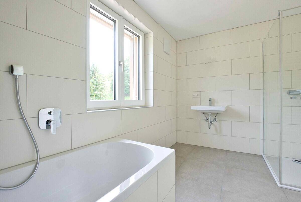 Modernes Badezimmer mit Badewanne, Dusche, Einzelwaschbecken und einem Fenster.