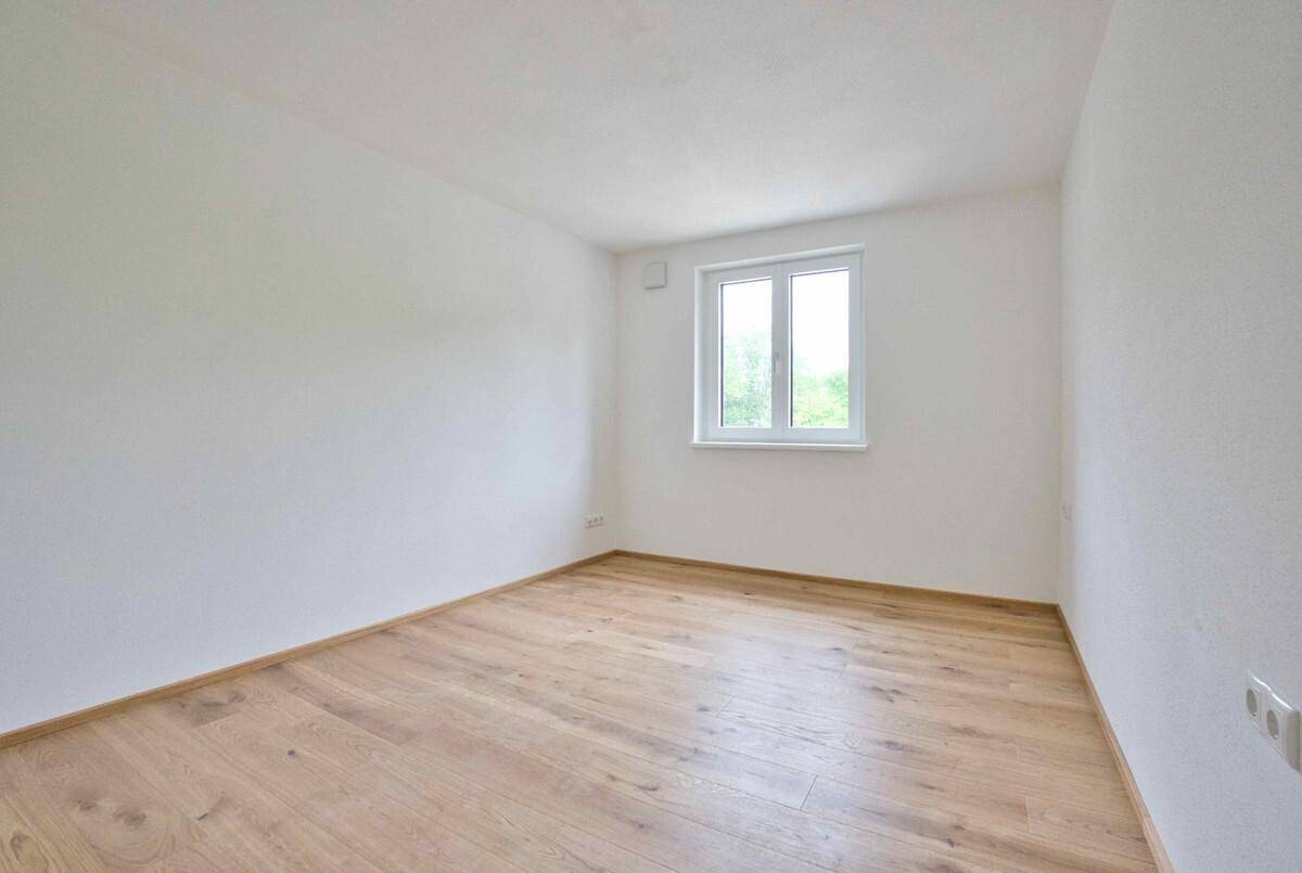 Kleineres, unmöbliertes Zimmer mit hellem Holzboden und einem Fenster für Tageslicht.