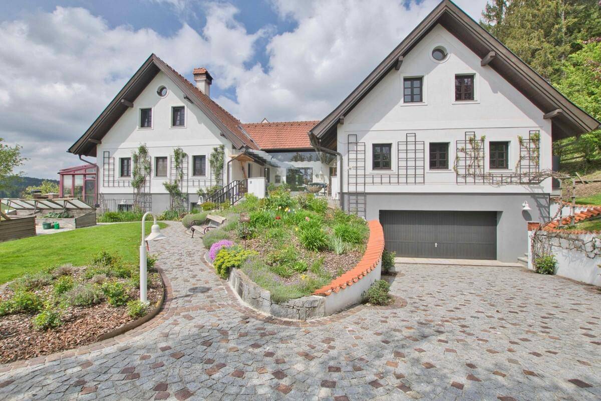 Vorderansicht des Hauses mit gepflasterter Auffahrt, Garage und liebevoll angelegten Blumenbeeten.