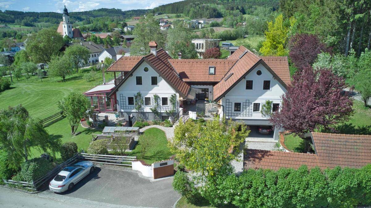 Weitläufige Luftaufnahme des Anwesens mit gepflegtem Garten, Einfahrt und ländlicher Umgebung.