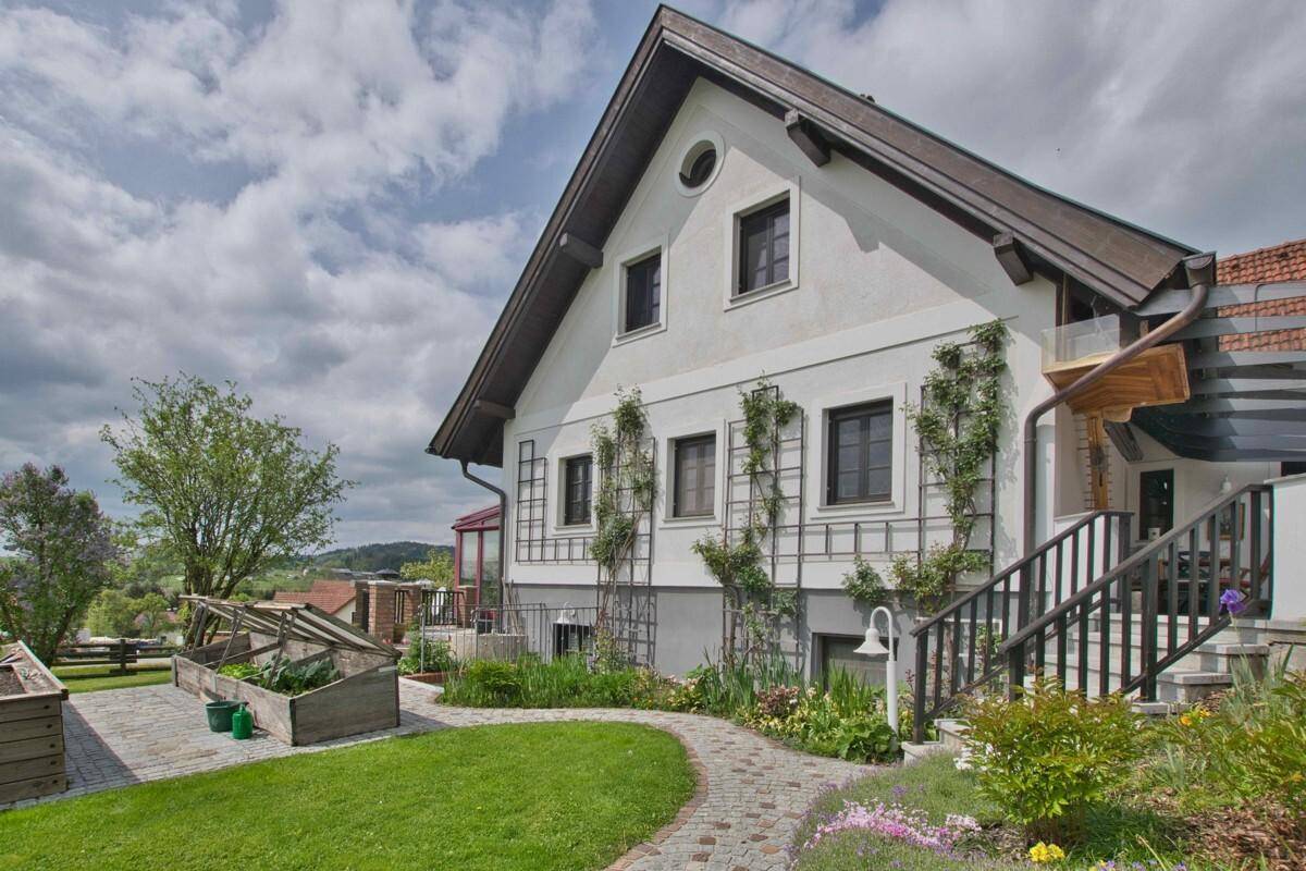 Seitenansicht des Hauses mit erhöhtem Gartenbeet, Rasenfläche und Blick in die Ferne.