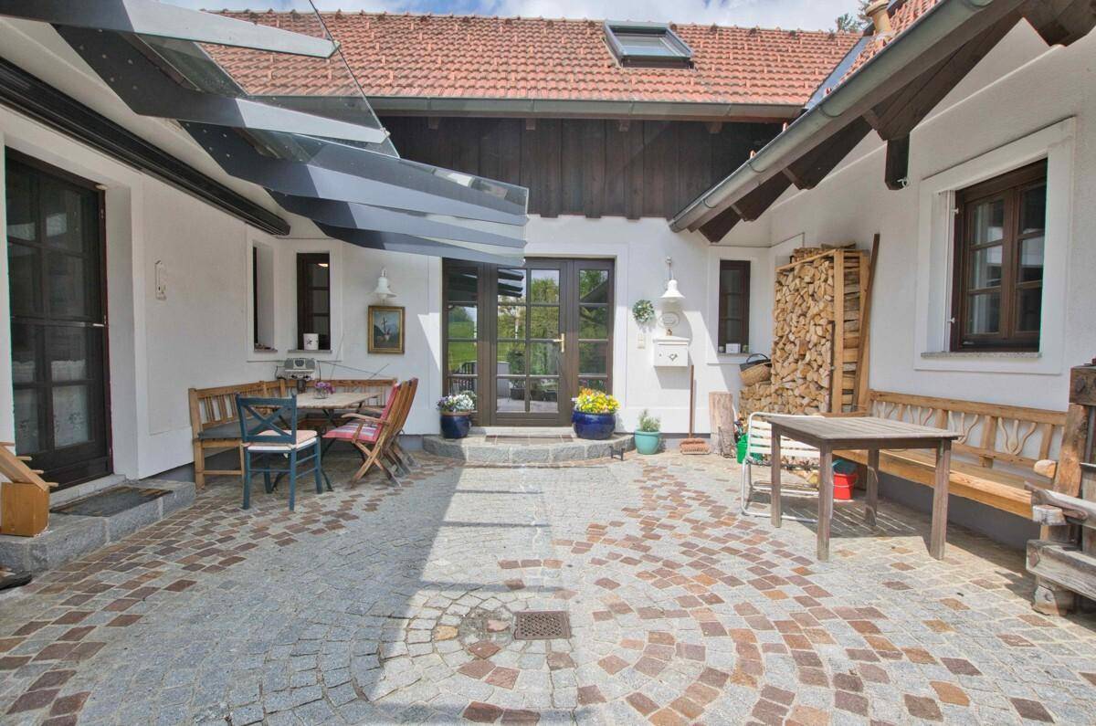 Gemütlicher Innenhof mit Sitzgelegenheiten, Holzlager und Zugang zu den verschiedenen Gebäudeteilen.