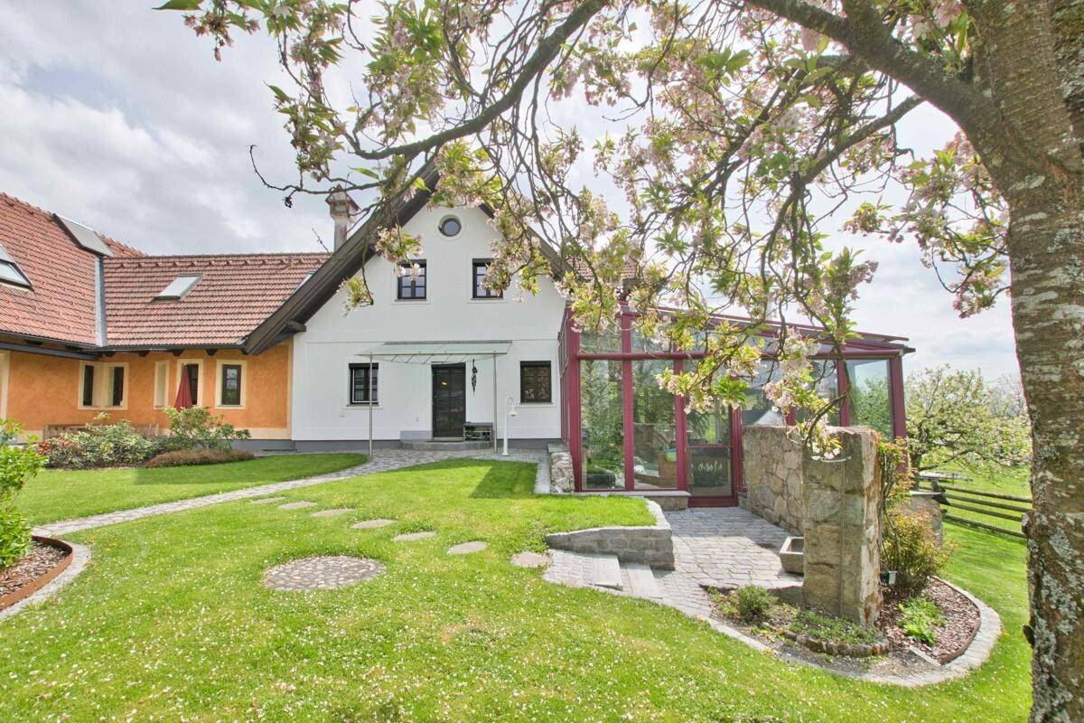 Rückseite des Hauses mit Wintergarten, kleiner Terrasse und weitläufigem, gepflegtem Garten.