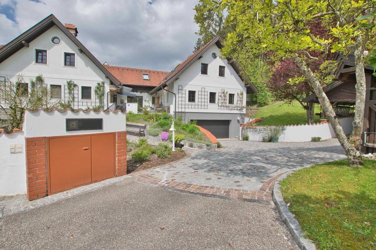 Eingangsbereich des Hauses mit gepflasterter Auffahrt, Garage und gepflegter Vorgartenbepflanzung.