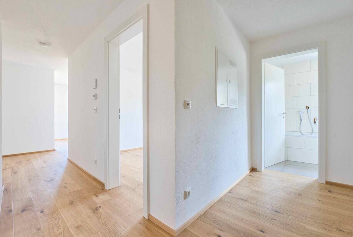 Heller Flur mit Holzboden, der zu verschiedenen Zimmern und einem Badezimmer führt.