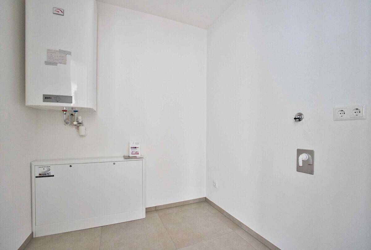Praktischer Hauswirtschaftsraum mit Warmwasserbereiter und Anschlüssen für Waschmaschine und Trockner.