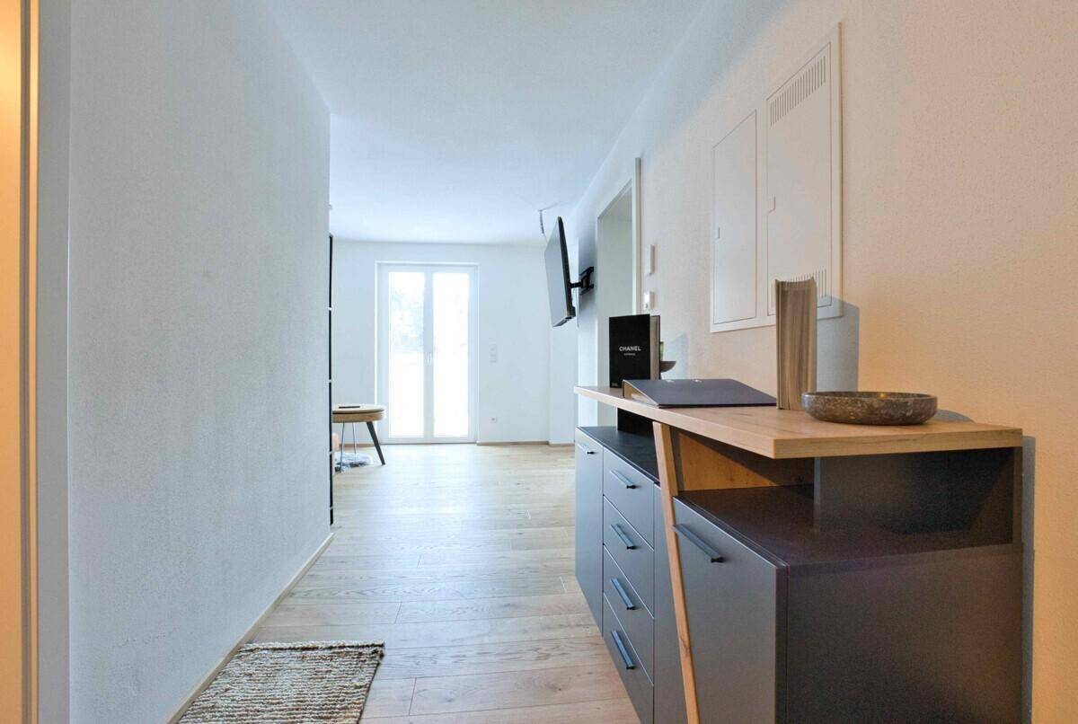 Moderner Flur mit Holzboden und stilvoller Kommode, führt in den Wohnbereich.