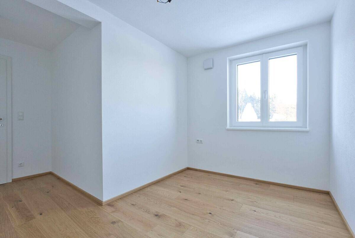 Helles Zimmer mit Holzboden und weiß gestrichenen Wänden, bereit zur individuellen Gestaltung.