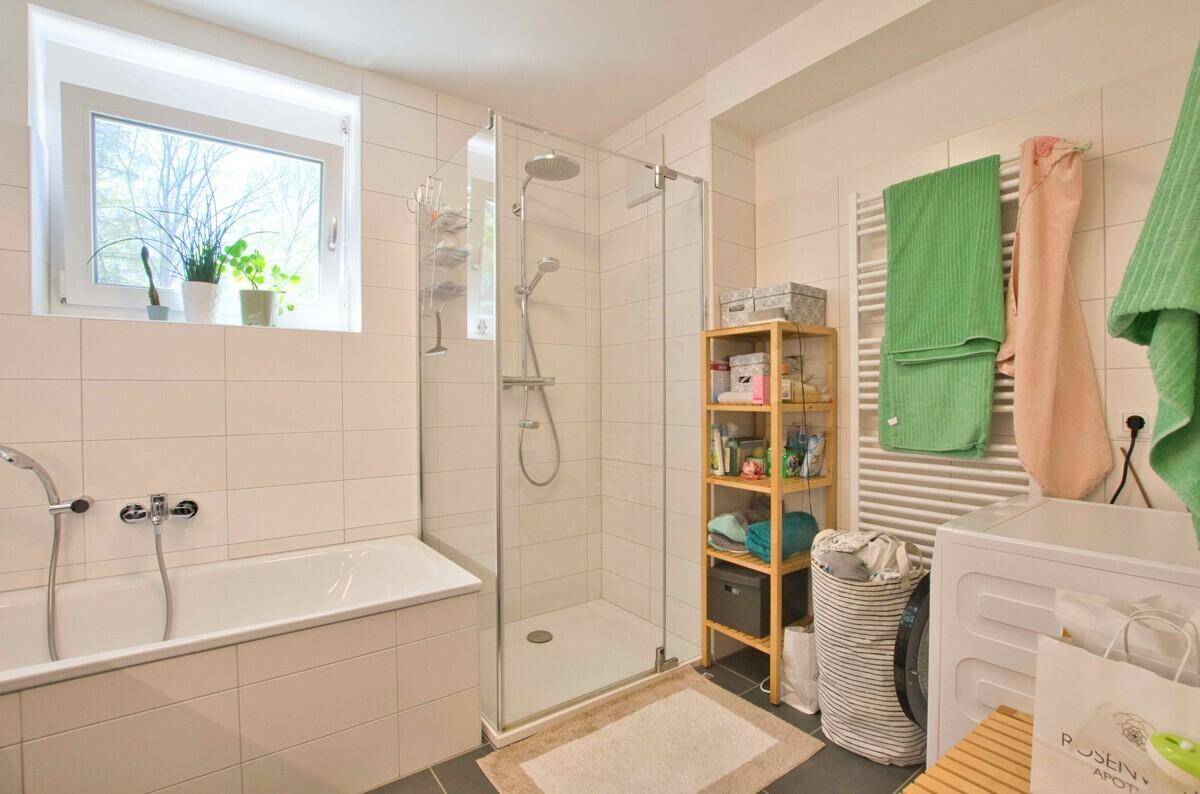 Geräumiges Badezimmer mit begehbarer Dusche, Badewanne und beheiztem Handtuchhalter.
