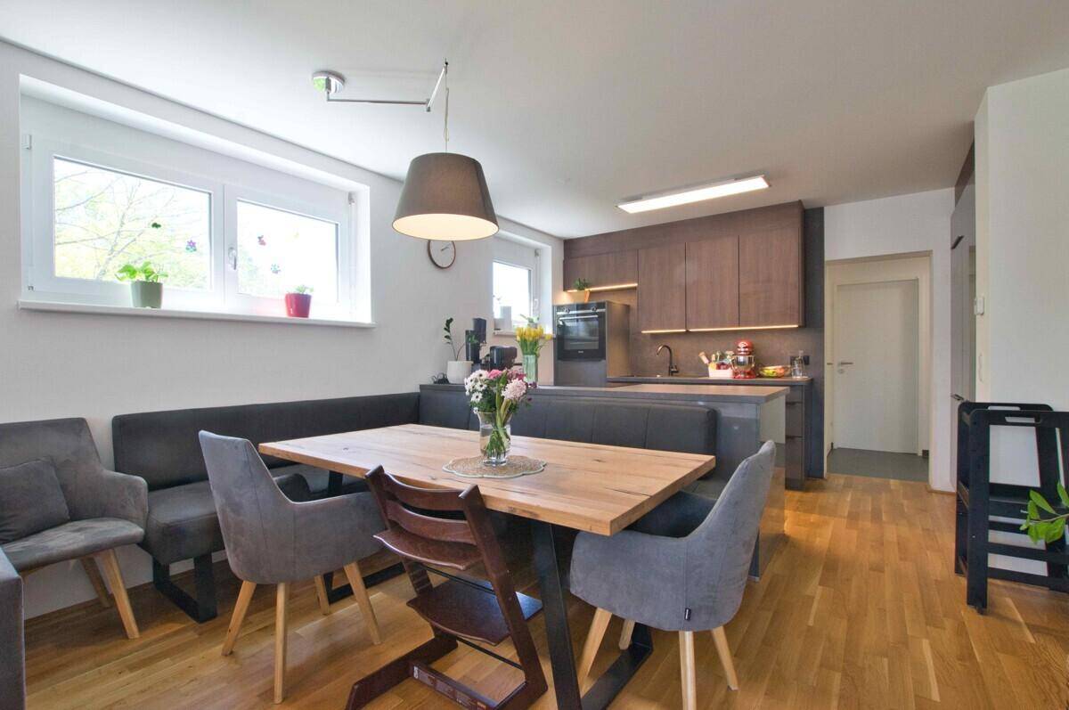 Gemütlicher Essbereich mit Holztisch und Sitzbank, direkt an die moderne Küche angrenzend.