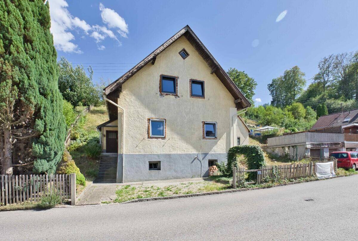 Vorderansicht des Hauses mit Satteldach, Fenstern und Zugang von der Straße.