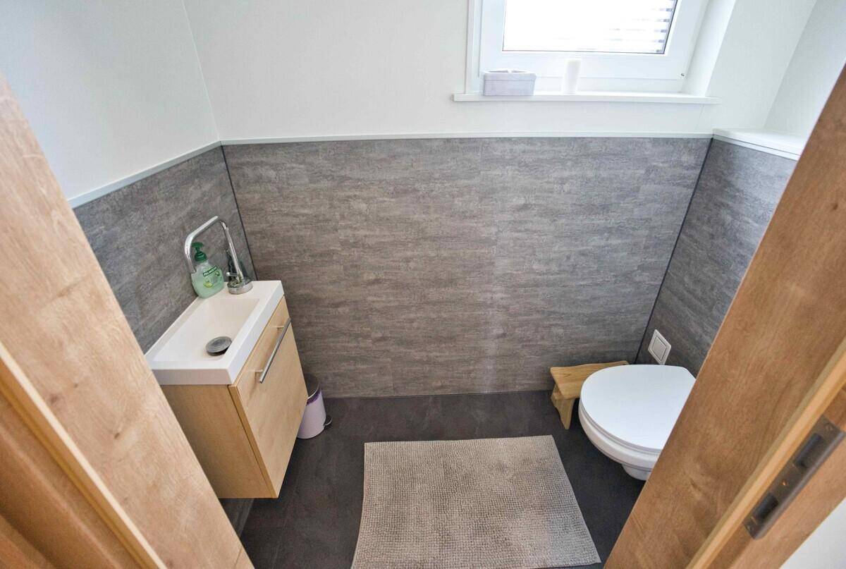 Separates WC mit Toilette, kleinem Waschbecken und Fenster für Belüftung.
