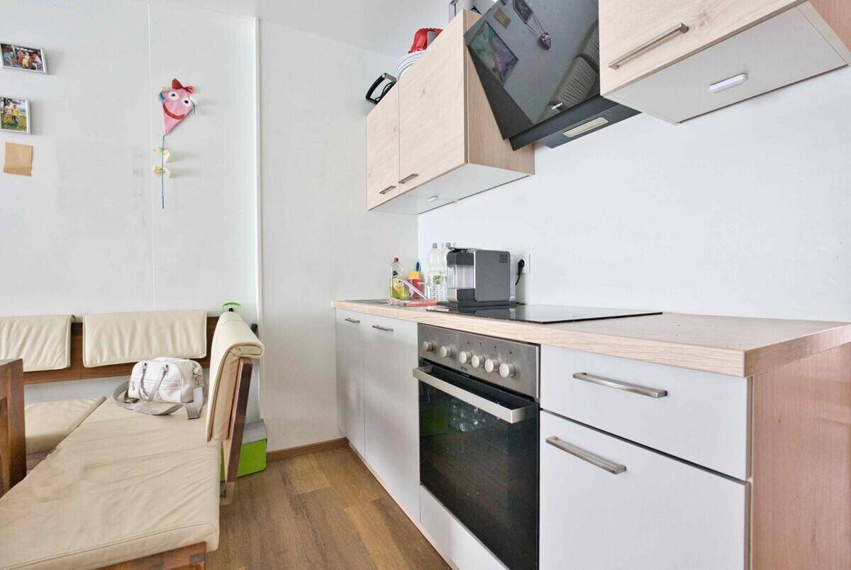 Moderne Küchenzeile mit Induktionskochfeld, Backofen und Dunstabzugshaube.