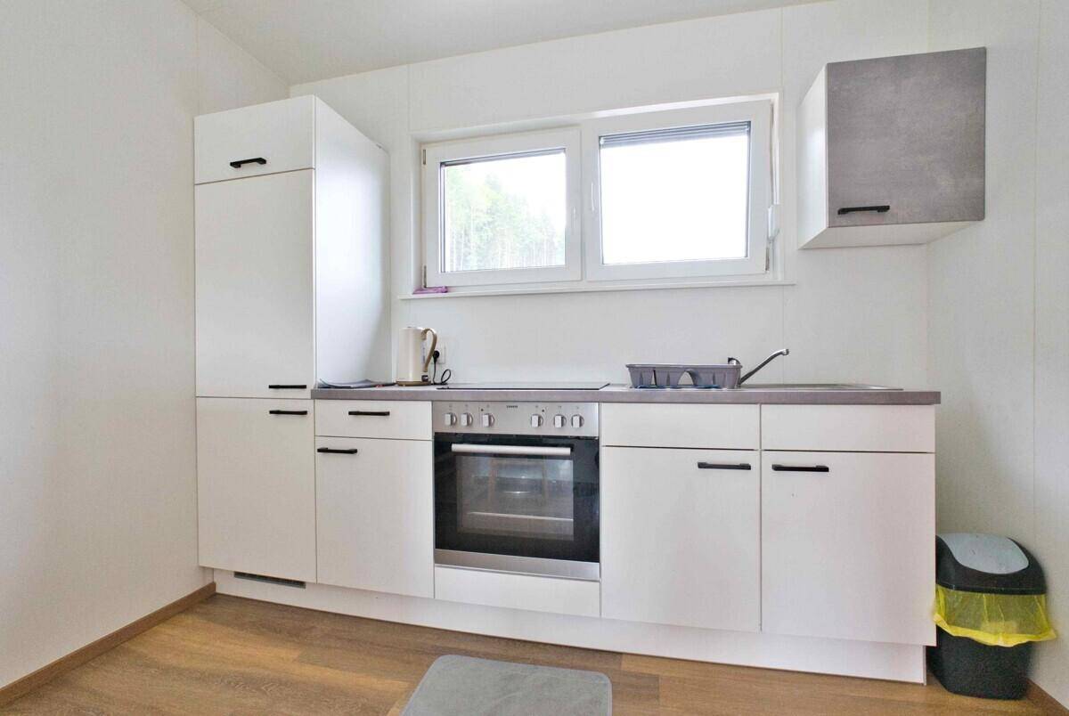 Moderne Küchenzeile mit weißen Schränken, Backofen und Fenster für Helligkeit.
